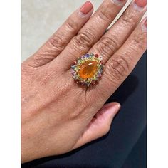 This is part of Chairish’s Fine Jewelry assortment.  7.11 Carat Pear Cut Natural Fire Opal Sapphire Yellow Gold Cocktail Ring  Item Specs:  Natural Orange Fire Opal (Pear Cut) = 3.27 Carats 18 Natural Yellow Sapphires (Round Cut) = 1.32 Carats 20 Natural Multi-Color Sapphires (Round Cut) = 2.52 Carats Total Carat Weight = 7.11 Carats 14KY Gold = 7.3 Grams Ring Size = 7 (Complimentary ring sizing available upon request) Luxury Multi-stone Rings For Party, Yellow Gold Multi-stone Rings For Party, Elegant Multi-stone Orange Rings, Elegant Orange Multi-stone Rings, Luxury Opal Ring With Gemstone Accents For Anniversary, Luxury Multi-stone Rings, Luxury Multicolor Sapphire Ring For Formal Occasions, Formal Multicolor Opal Gemstone Ring, Luxury Opal Ring With Accent Stones For Formal Occasions