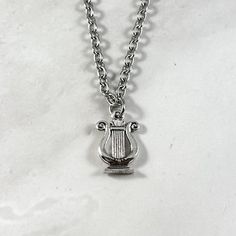 This beautiful chain necklace is the perfect way to express your affinity for Apollo or Ancient Greece. Made with a double sided Ancient Greek style lyre charm.  Secures with a lobster clasp. Chain is stainless steel and is available in a variety of lengths. (A two inch extender can be added to the end upon request.) Charm is made of pewter and is silver plated. Chain is stainless steel. All materials are lead and nickel free. Charm measures about 0.5 inches long. Pictured with a coin to give an Lyre Necklace, Apollo Necklace, Greek Mythology Jewelry, Dragon Born, Mythology Jewelry, Jewelry Ancient, Silver Jewlery, Greek Style, Ancient Greece