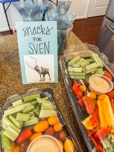 two plastic containers filled with veggies next to a sign that says snacks for seven