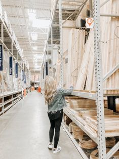 a woman is looking at wooden planks in a store aisle with shelves full of wood