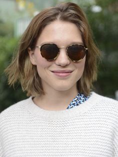 a woman wearing sunglasses and smiling for the camera with her hair in a bobble