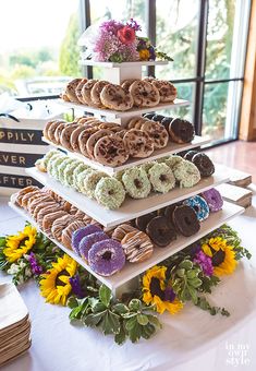 a stack of doughnuts sitting on top of a table next to sunflowers