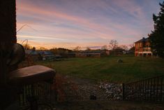 the sun is setting over an open yard