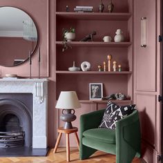 a living room filled with furniture and a fire place in front of a pink wall