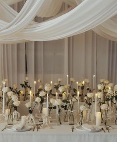 a table topped with lots of white flowers and candles