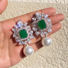 Emerald and Pearl earrings featuring semi precious green stone and white pearl with cz diamonds. These HIGH Quality Emerald Diamond Earrings are surely elevate your look. Perfect gift for her. *𝐏𝐑𝐎𝐃𝐔𝐂𝐓 𝐃𝐄𝐓𝐀𝐈𝐋* * 𝐌𝐚𝐭𝐞𝐫𝐢𝐚𝐥: Brass * 𝐏𝐥𝐚𝐭𝐢𝐧𝐠: White Rhodium Plated * 𝐒𝐭𝐨𝐧𝐞: AAA-quality CZ Diamond, Emerald & Pearl. *𝐃𝐈𝐌𝐄𝐍𝐒𝐈𝐎𝐍𝐒* * 𝐖𝐞𝐢𝐠𝐡𝐭: 14 gm each * 𝐋𝐞𝐧𝐠𝐭𝐡: 2 Inches * 𝐖𝐢𝐝𝐭𝐡:  1.5 mm * 𝐂𝐥𝐨𝐬𝐮𝐫𝐞: Push Back 𝐕𝐢𝐬𝐢𝐭 𝐎𝐮𝐫 𝐅𝐀𝐐𝐬 𝐟𝐨? Emerald Diamond Earrings, Earrings Luxury, Emerald Wedding, Pearl And Diamond Earrings, Pearl Earring, Green Diamond, Green Emerald, Cz Diamond, Emerald Diamond