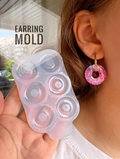 a close up of a person holding a pair of earring molds