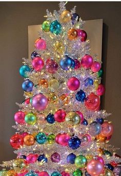 a brightly colored christmas tree is decorated with ornaments and tinsels, all in different colors