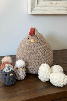 three crocheted chickens sitting next to each other on top of a wooden table