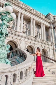 a woman in a red dress standing on some steps