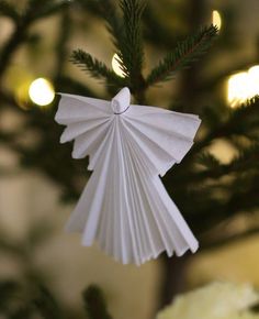 an ornament hanging from a christmas tree with lights in the background and text below it