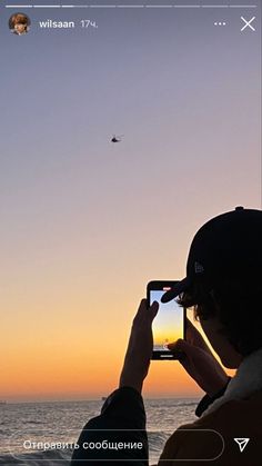 a person taking a photo with their cell phone at the beach during sunset or sunrise