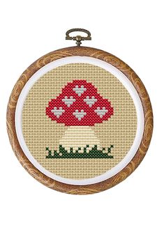 a cross stitch pattern with a red mushroom in the middle and green grass on it