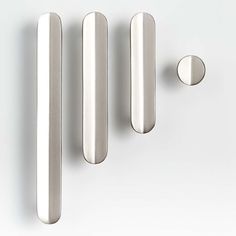 three stainless steel door handles and knobs on a white surface, with one in the foreground