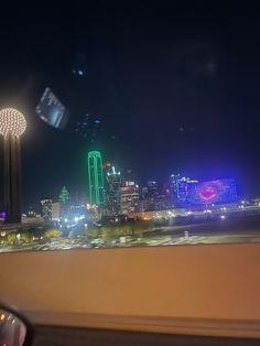 the city skyline is lit up at night from across the street, with lights in the foreground