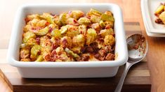 a casserole dish with meat and vegetables in it on a wooden cutting board