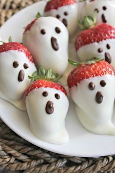 chocolate covered strawberries with white frosting in the shape of ghost faces on a plate