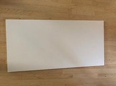 an empty piece of white paper sitting on top of a wooden floor