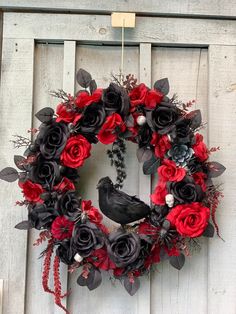 a wreath with black and red flowers hanging on a white door frame, decorated with a bird