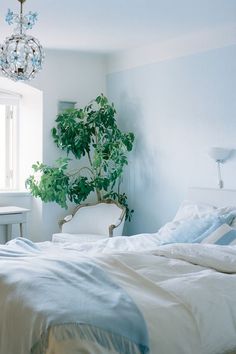 a bedroom with a bed, chair and potted plant