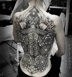 the back of a woman's body is covered in intricate designs and tattoos on her lower back