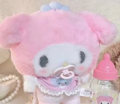 a pink stuffed animal with a pacifier in its mouth next to a teddy bear