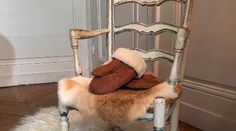 a chair with a pair of boots on top of the seat and a furry rug underneath it