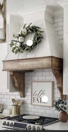 a white kitchen with a wreath on the stove top above it's range hood