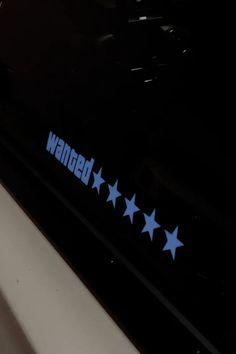 the word wanted is written in blue stars on a black background with white and gray stripes