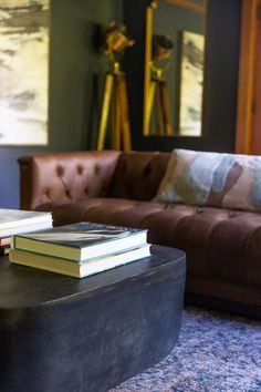 two books sitting on top of a coffee table in front of a couch and mirror