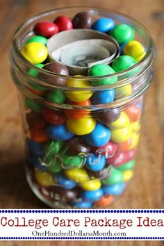 a glass jar filled with lots of colorful candies on top of a wooden table