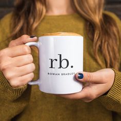 a woman holding a coffee mug with the letter rb on it's side