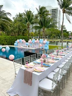 a table set up for a baby shower with balloons and decorations on the tables in front of an outdoor swimming pool