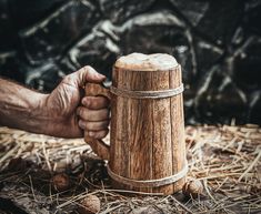 a person holding a wooden mug in their hand