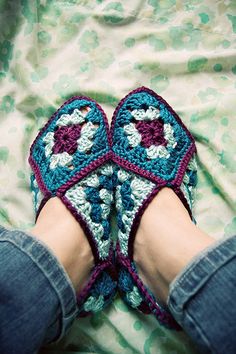 someone is wearing crocheted slippers on their feet and they are sitting on a blanket