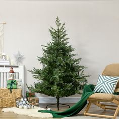 a small christmas tree in a living room next to a chair and other holiday decorations