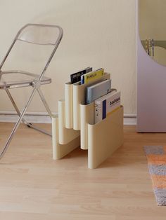 a stack of books sitting on top of a wooden floor next to a folding chair