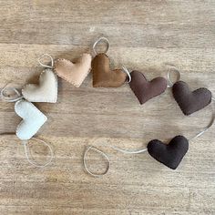 five heart shaped ornaments are tied together on a wooden surface with string attached to them