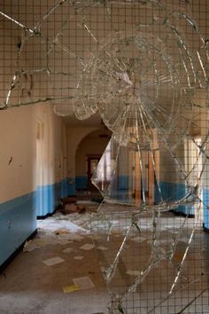 a broken glass window in the middle of an empty room with blue and white walls