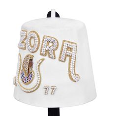 The DOI PHA fez is crafted from 100% wool Pure White and boasts a ventilated top for added warmth and durability. It is adorned with a double row of rhinestones on the letters above the emblem. Top-quality materials and skilled craftsmanship make this fez a durable accessory. It includes the Daughters Of Imperial Court Masonic emblem, and also offers 10 free letters included with the option to customize your lodge name, number, city, and state, and comes with a 15" size tassel.Additional Rhinest Fez Hat, Masonic Gifts, Brick Mason, Tied T Shirt, Masonic Ring, Free Lettering, Custom Ties, Gold Embroidery, Pure White