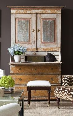 a living room with an old dresser, chair and vase on the coffee table in front of it