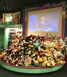 a large amount of stuffed animals in front of a projection screen at disney's art of animation