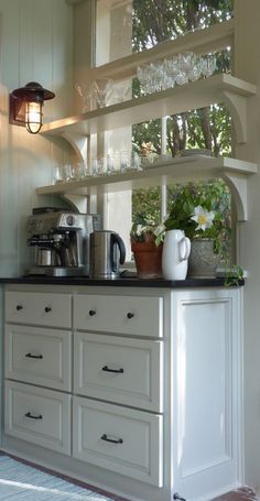 a kitchen with white cupboards and glassware on the top shelf next to an open door