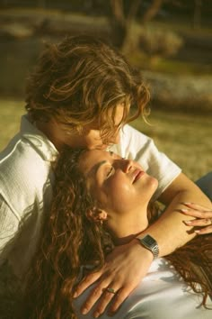 a man and woman laying on the ground with their arms around each other as they hug