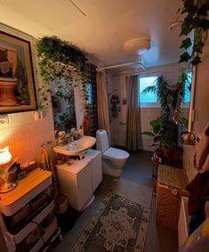 a bathroom with a sink, toilet and plants in it