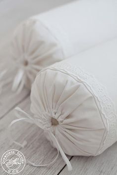 two rolls of white wedding garters sitting on top of a wooden floor next to each other