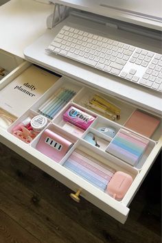 a computer desk with a keyboard, mouse and various office supplies in drawers on it