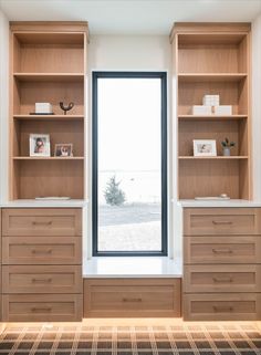 an empty room with wooden shelves and drawers in front of a large window, looking out onto the ocean