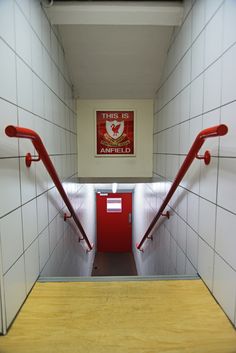 this is an empty hallway with red handrails and white tiles on the walls