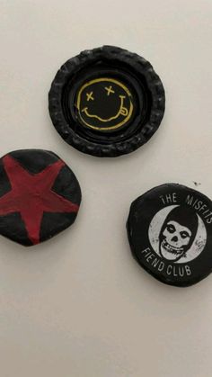 three badges on a white surface one with a skull and the other with a red star